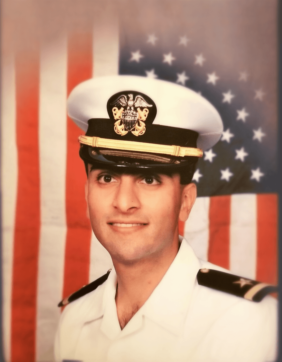 Navy Surface Warfare Officer in white dress uniform with American flag background